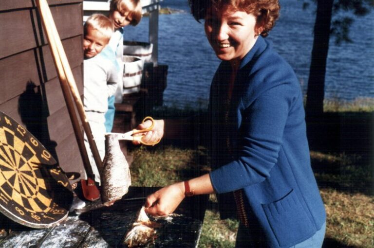 Mom cleaning a fish while kids look on - creating memories with family.