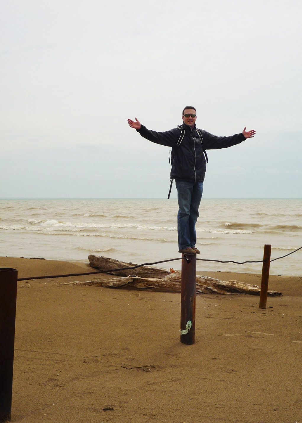 Man standing on a post on the beach at Long Point Provincial Park. 
