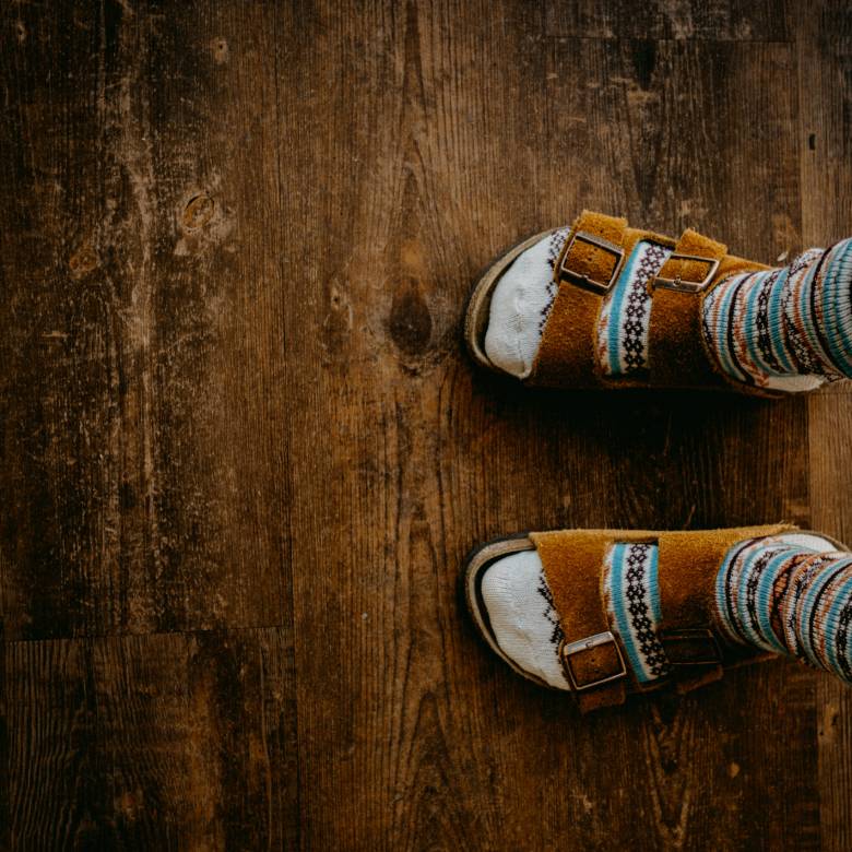 Faceless person wearing funky socks with Birkenstock sandals - funny life goals list.