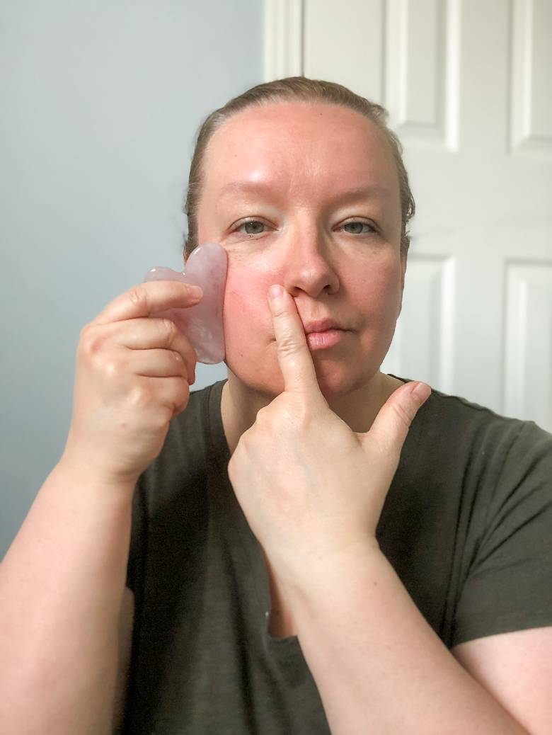 Woman using a gua sha tool - gua sha face massage routine. 