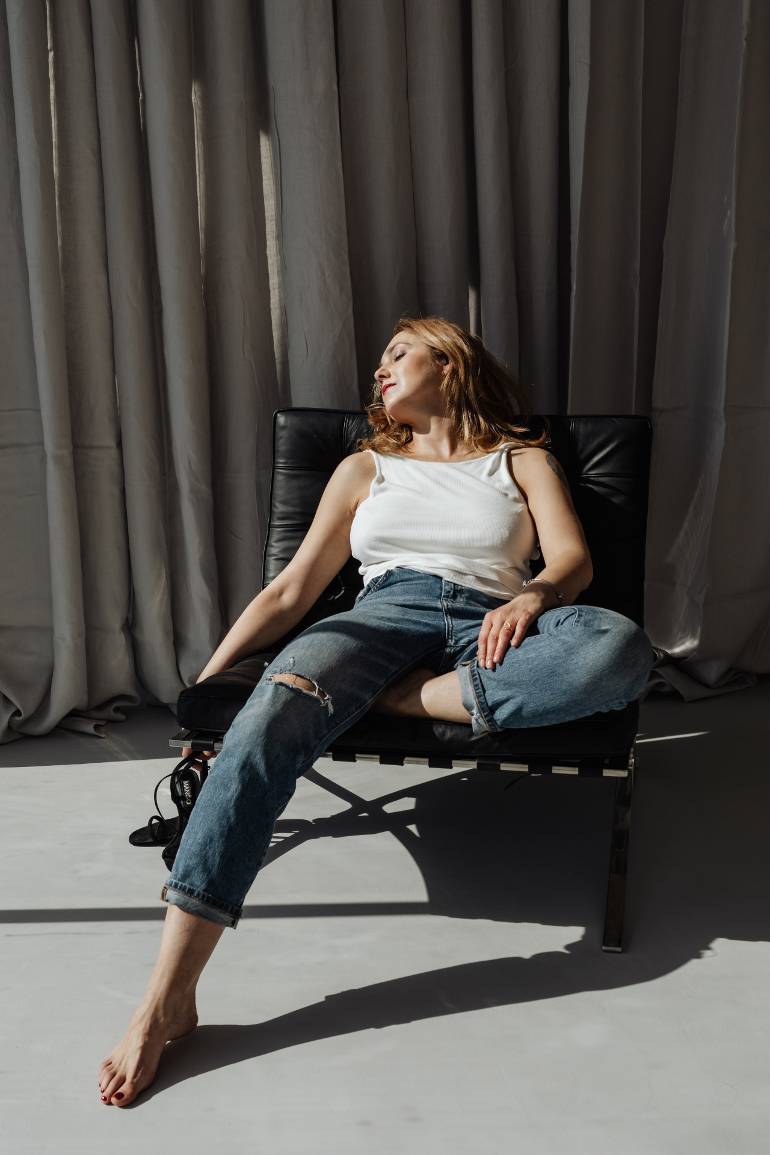 A woman relaxing in the sunshine in a black chair with her eyes closed - a blog post on how to get back to a productive routine when you've been distracted.
