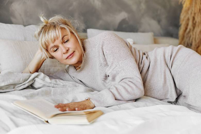 Woman on a bed reading a book - quotes about finding yourself again.