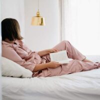 Woman in bed, with a book - relaxing Sunday night routine