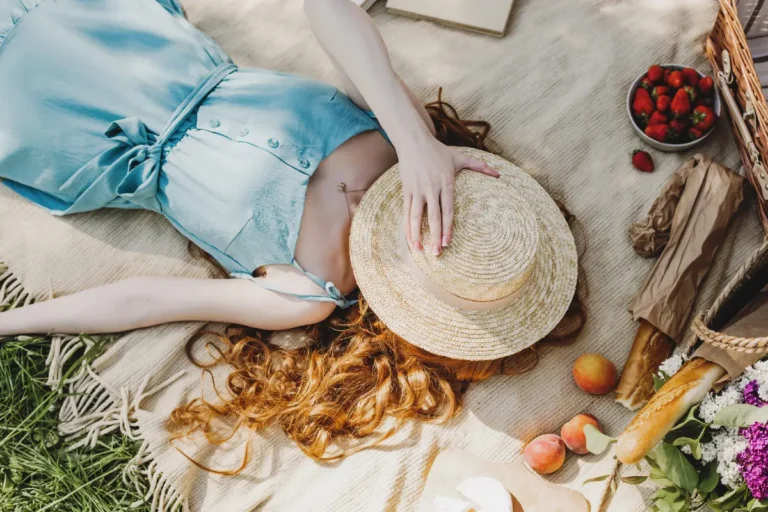 Woman laying down on a blanket with picnic - things to do in the summer by yourself.