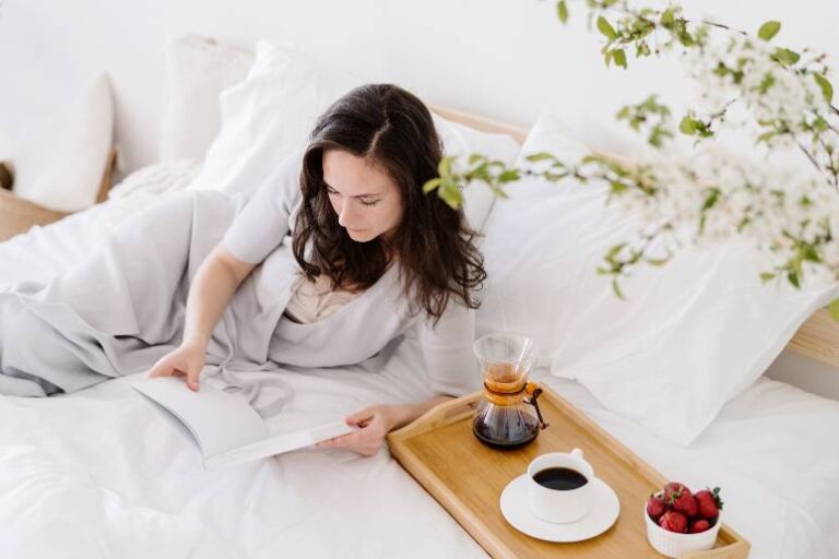 Woman laying on a bed with a coffee on a tray - ways to be happier in your 40s.