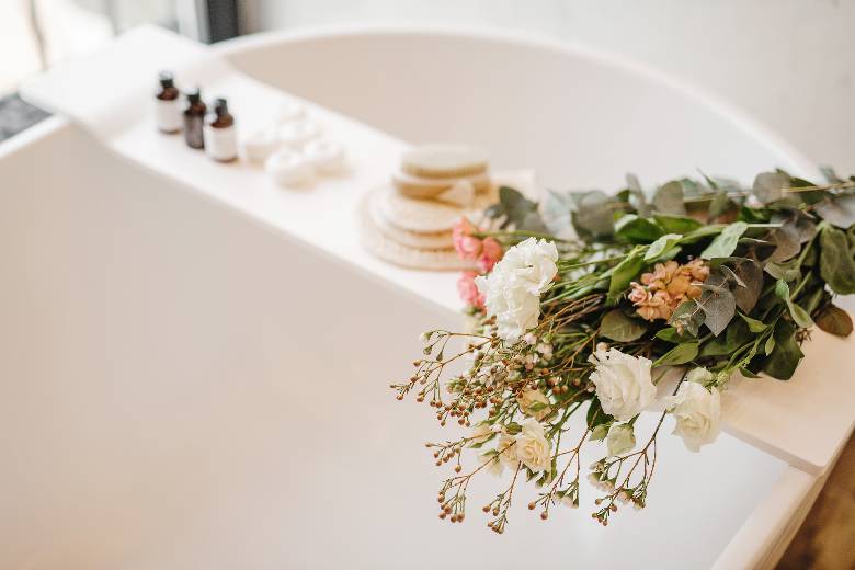 Bath tub with a wood shelf and flowers and other spa essentials - how to pamper yourself after giving birth.