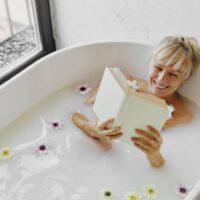 Woman in a bathtub reading - winter self-care ideas.